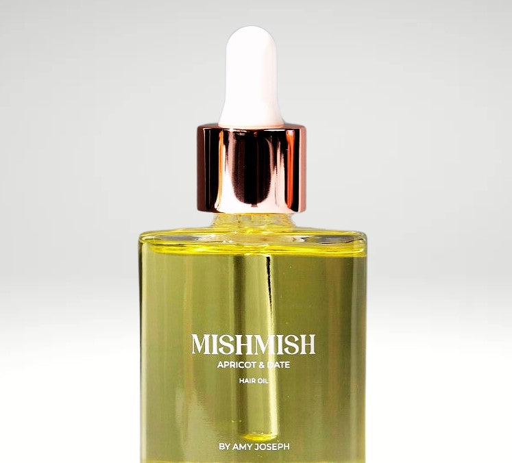 Hands holding up the two sizes of MISHMISH hair oil